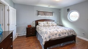 Un dormitorio con cama de madera, mesita de noche, cómoda y ventana con vistas.
