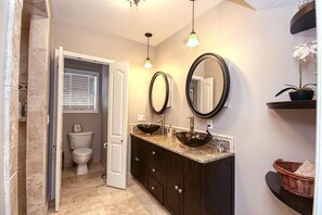 A bathroom with a dark vanity, two vessel sinks, a large mirror, and a potted orchid. - Just steps to the Boardwalk and Ocean this is a spacious 5 bed 3 full bath home! (Seaside Park)