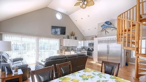 Amplia sala de estar con una mesa de comedor, sofá y cocina al fondo.