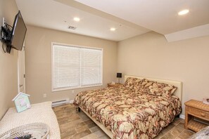 A bedroom with a large bed, a television mounted on the wall, and a window with blinds. - Just steps to the Boardwalk and Ocean this is a spacious 5 bed 3 full bath home! (Seaside Park)