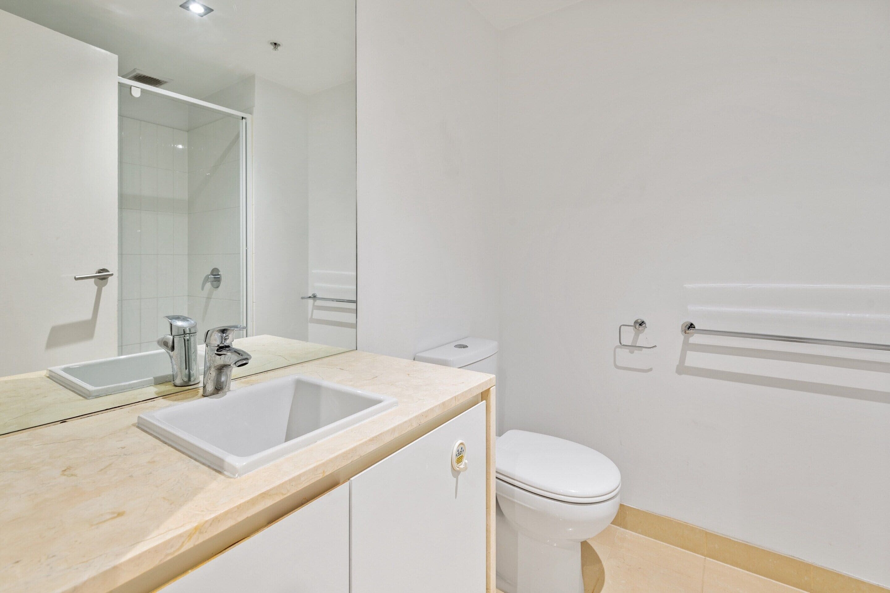 A modern bathroom with a sink, mirror, toilet, and shower.