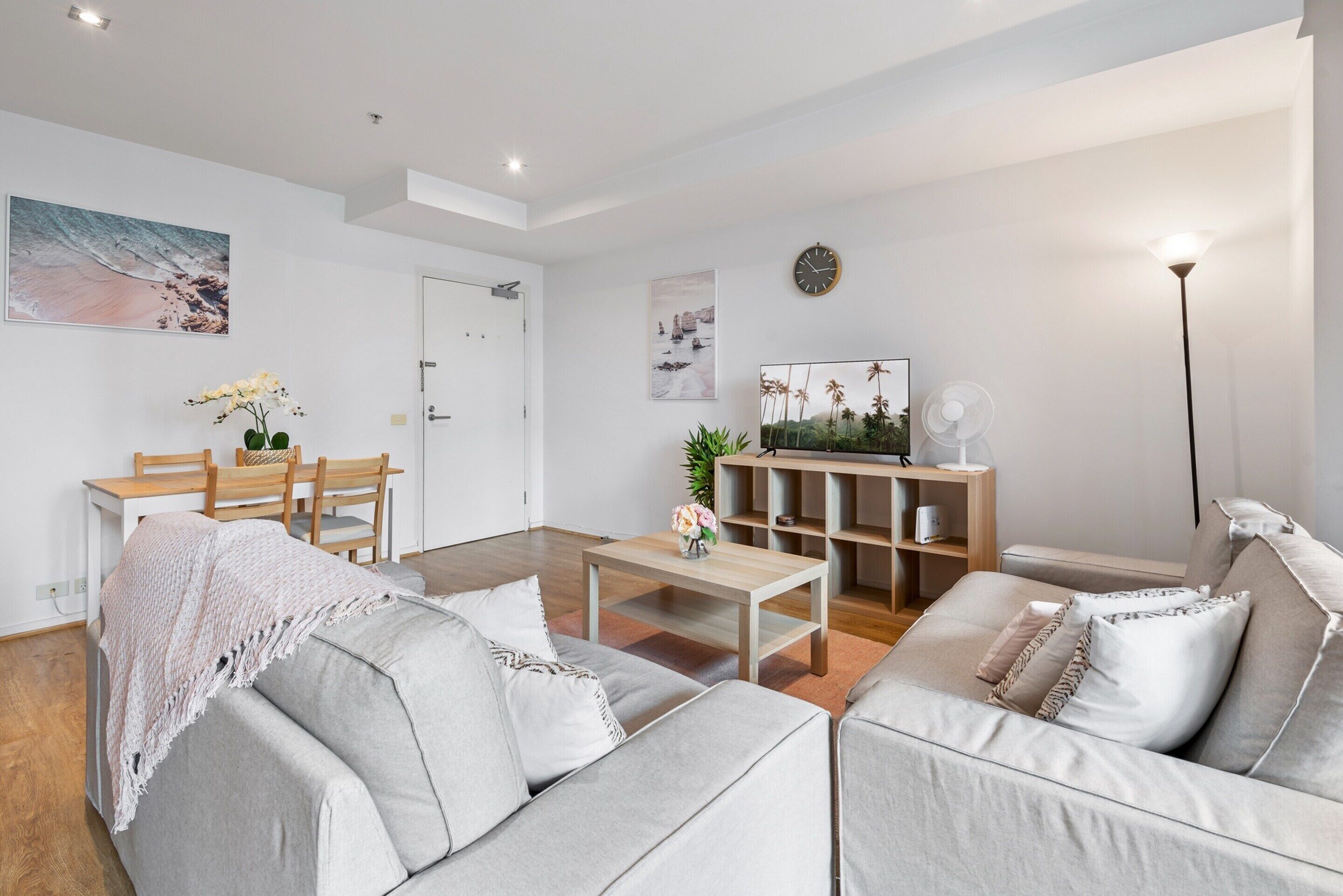 En moderne stue med sofa, sofabord og spiseplads med stole og bord.
