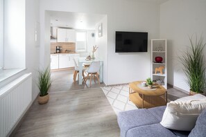 A modern living room with a sofa, a coffee table, and a TV mounted on the wall.