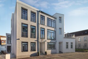 A multi-story building with a flat facade, large windows, and a balcony on the second floor.