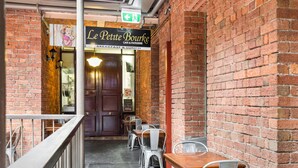 An outdoor cafe with brick walls, metal chairs, and tables. - Cosy and Central City Studio Near Attractions (Melbourne)