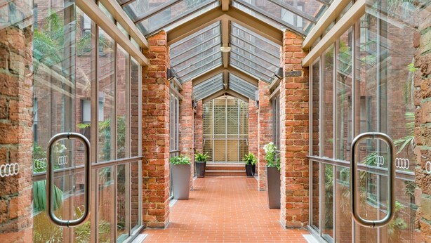 A corridor with brick walls, large windows, and metal railings. - Cosy and Central City Studio Near Attractions (Melbourne)