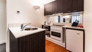 Une cuisine de taille réduite, équipée d’un évier, d’une cuisinière, d’un four et d’un réfrigérateur.