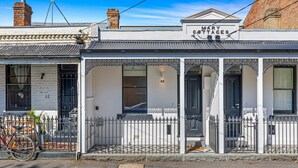 Un edificio blanco con una cerca de hierro negro y un letrero que dice "Mary Cottages".