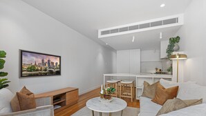 Una sala de estar moderna con un sofá blanco, una mesa de centro redonda y una pintura de paisaje urbano en la pared.
