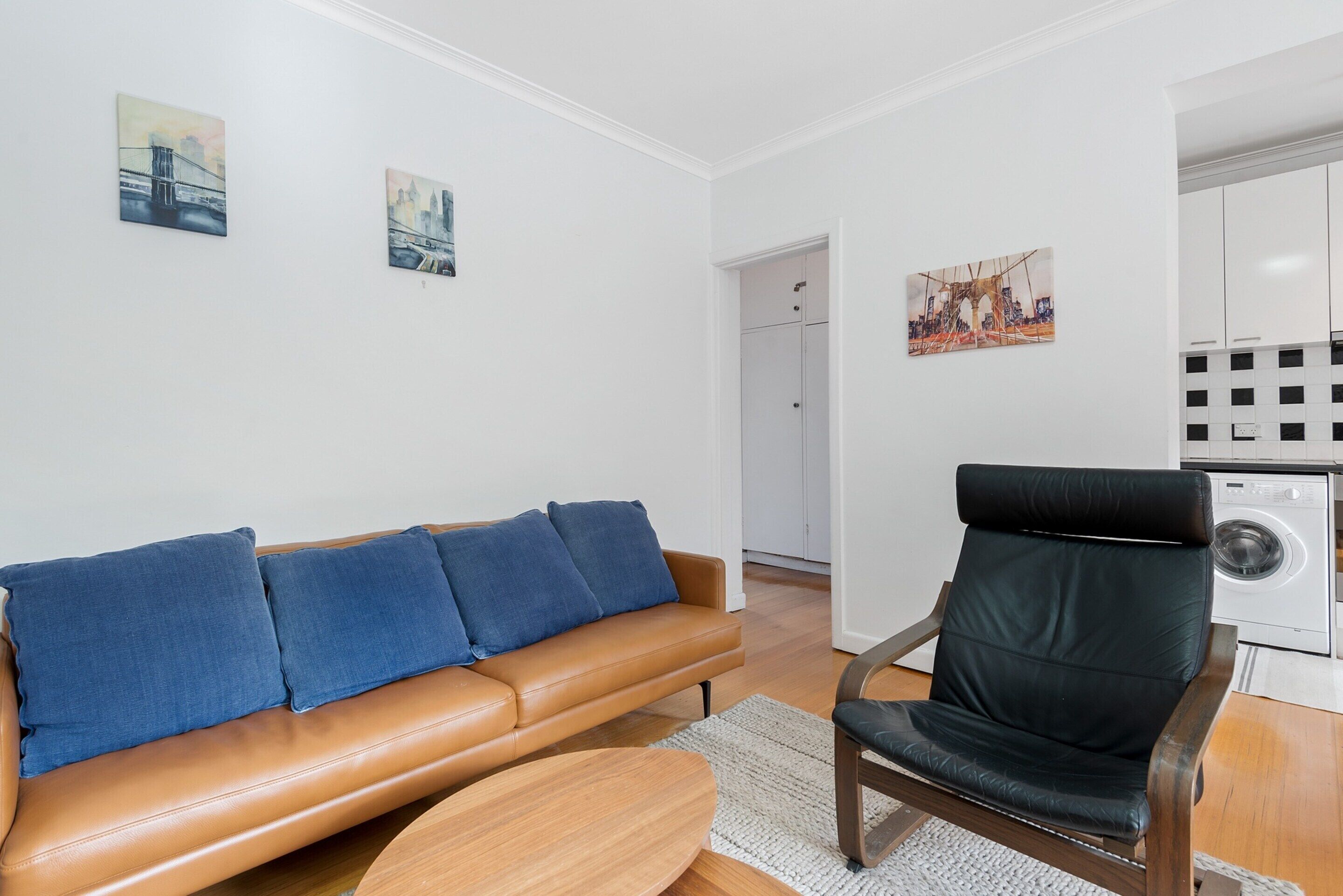Ein modernes Wohnzimmer mit einer Ledersofa, einem schwarzen Sessel und Kunstwerken an den Wänden.