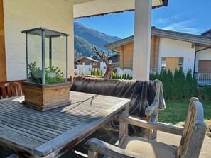 Ein Holztisch mit Glaseinsatz, eine mit Fell bezogene Bank und eine Hirschskulptur.