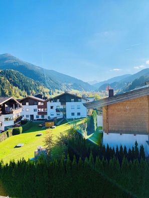 A mountain village with traditional buildings, a green valley, and a clear sky.