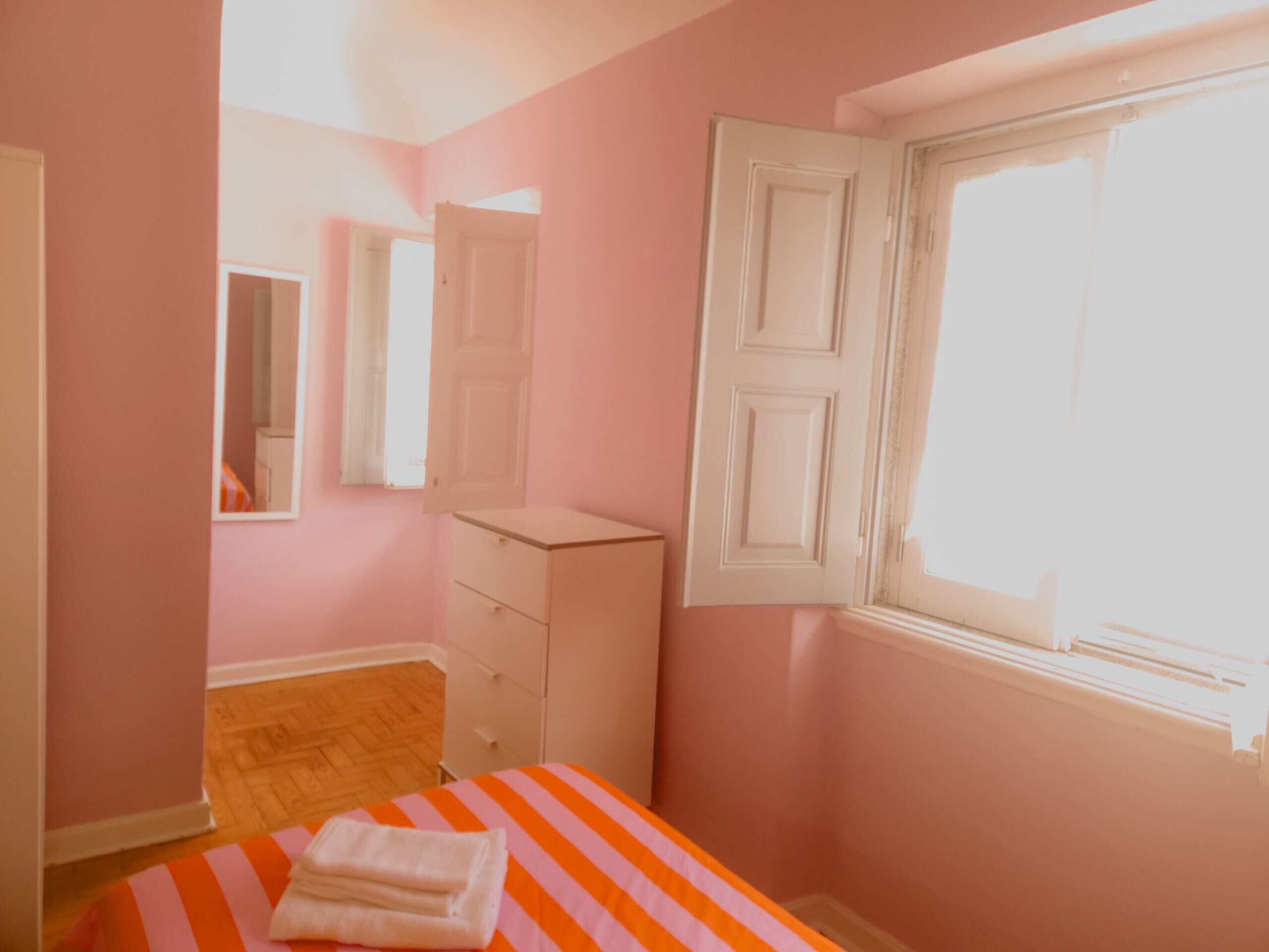 A bedroom with a bed, a dresser, a mirror, and a window.