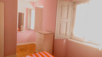 A bedroom with a bed, a dresser, a mirror, and a window.