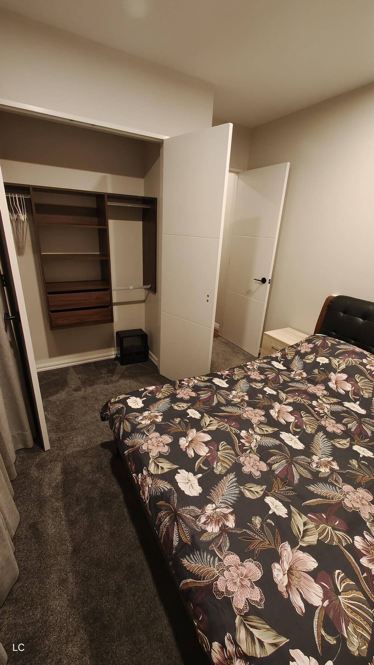 A bedroom with a bed, a wardrobe, and a desk.