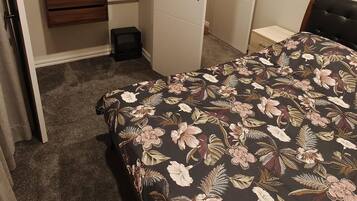 A bedroom with a bed, a wardrobe, and a desk.