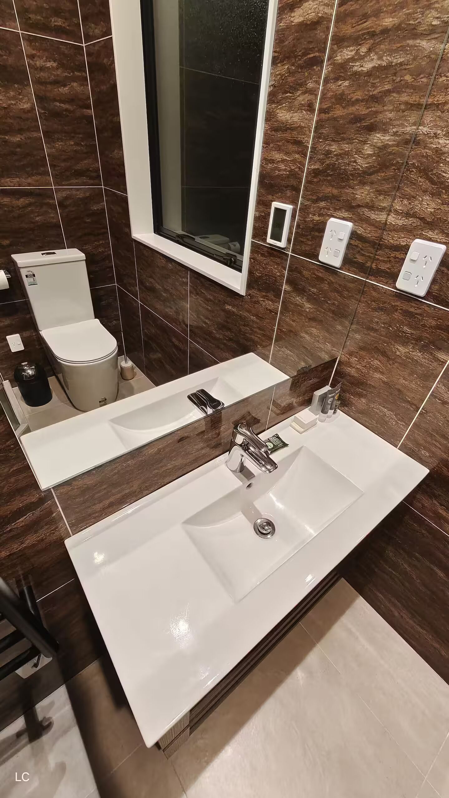 Une salle de bain moderne avec deux lavabos, des toilettes et un grand miroir.