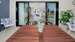 Een eethoek met een houten tafel, twee witte stoelen met blauwe patronen en een kamerplant.