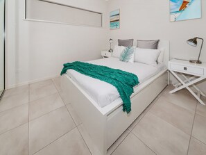 Ein Schlafzimmer mit einem Bett, Nachttischen, einer Lampe und Kunstwerken an den Wänden.