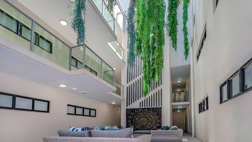 Un vaste atrium doté d’un haut plafond, agrémenté de plantes suspendues et comprenant un espace détente avec des coussins.
