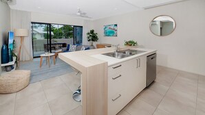 Een moderne keuken met een centraal eiland, een zithoek met stoelen en een groot raam met uitzicht op het omliggende landschap.