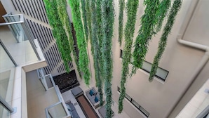 Een modern gebouw met een balkon, een terras en hangende planten.