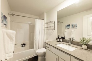 Une salle de bain équipée d’une douche, de toilettes, d’un lavabo et d’un miroir.