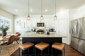 A modern kitchen with white cabinets, stainless steel appliances, and a central island with bar stools.