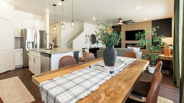 A modern kitchen with stainless steel appliances, a dining area with a wooden table, and a living space with a sofa and a TV. - Park City Redbud Hideaway | Modern 6BR Mountain Retreat w/ Hot Tub & Views (Park City)