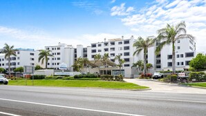 A multi-story hotel with a modern design, featuring a covered entrance and palm trees. - Beachside 3-bed With Bbq, Pool, Gym (Sunshine Coast)