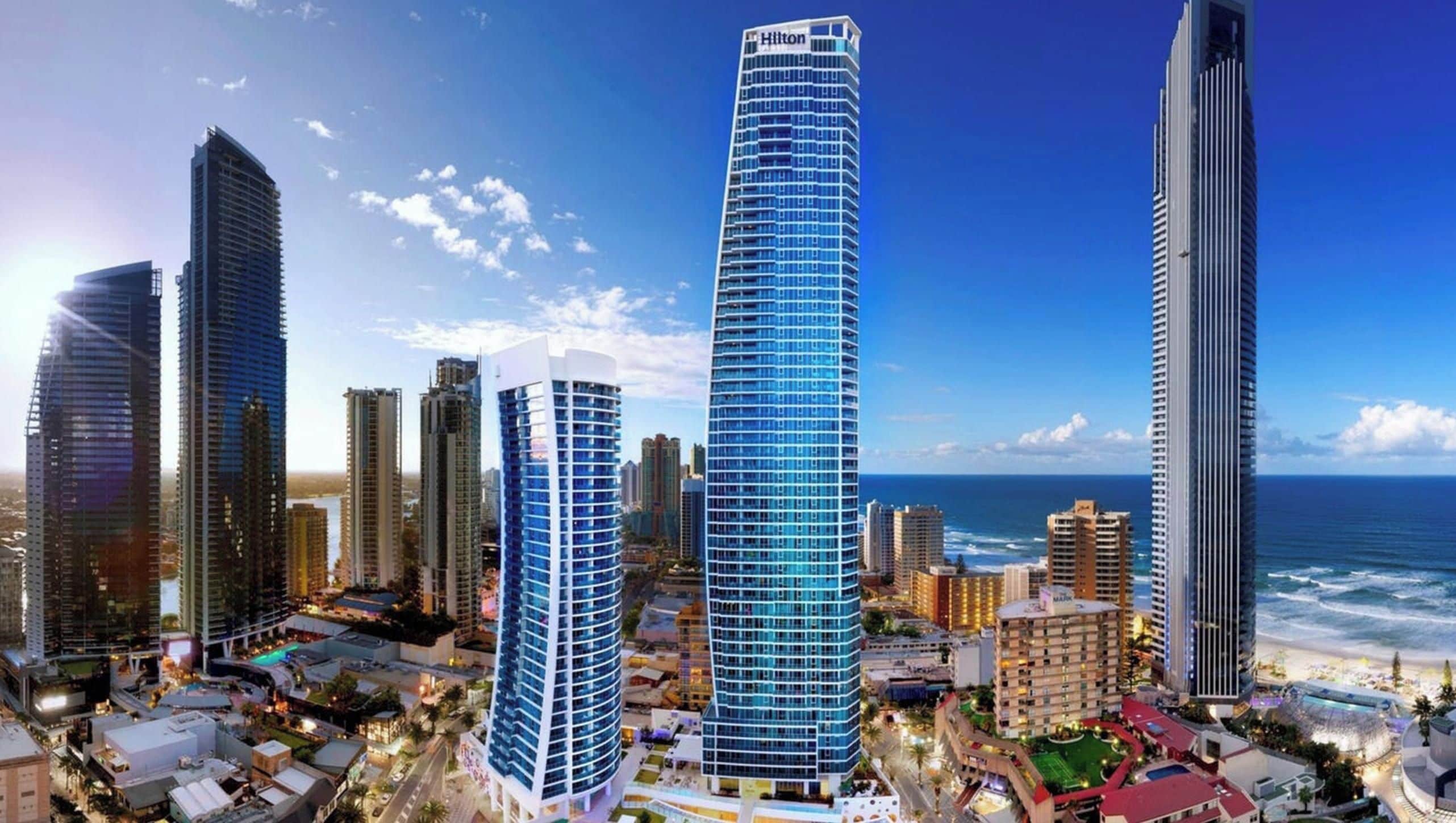 Een hoog hotel met een gebogen gevel, nabij een strand en met uitzicht op de oceaan.