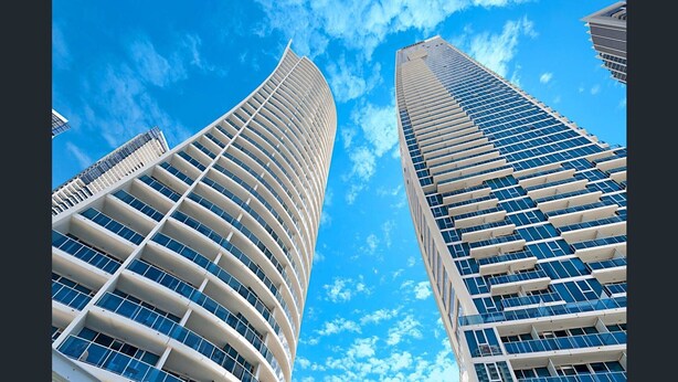 Deux immeubles de grande hauteur, dotés d’une façade incurvée, se dressent sur fond d’un ciel bleu azur.