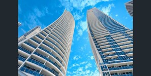 Two high-rise buildings with a curved facade and a clear blue sky in the background. - Modern 2-bed With Pool Access in Surfers Paradise (Gold Coast)
