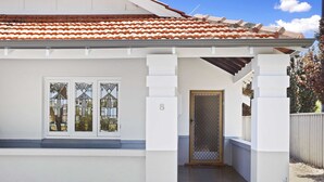 A house with a white exterior, a tiled roof, a front door with a glass panel, and a number '8' on the wall. - Chic Semi-detached 2-bed Home With Outdoor Dining (Perth)