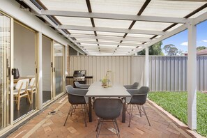 An outdoor patio with a table and chairs, a grill, and a covered area with a white roof. - Chic Semi-detached 2-bed Home With Outdoor Dining (Perth)
