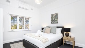 A bedroom with a bed, bedside table, lamp, and a window with stained glass. - Chic Semi-detached 2-bed Home With Outdoor Dining (Perth)