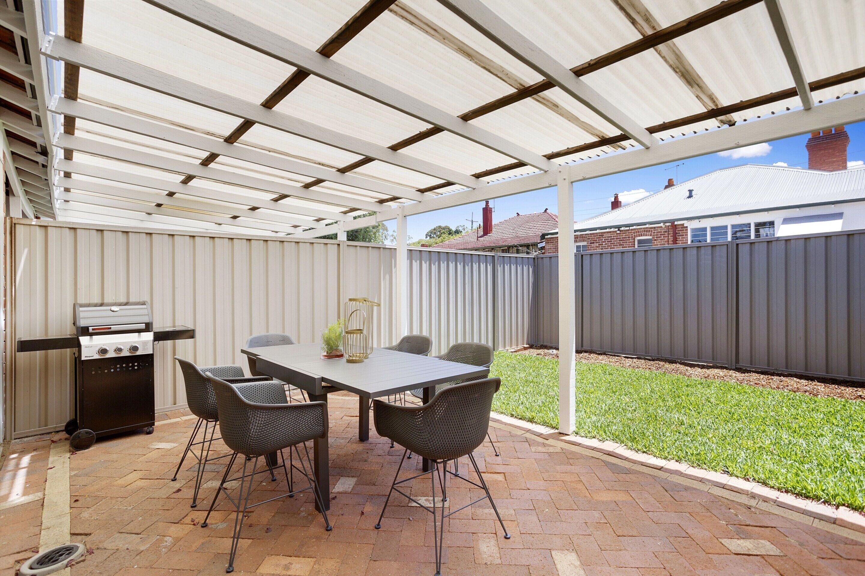 Une terrasse extérieure équipée d’un barbecue, d’une table et de chaises.