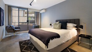 Une chambre moderne avec un grand lit, une chaise, une table de chevet et une fenêtre donnant sur un beau paysage.