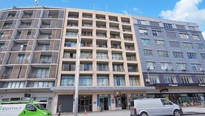 Un immeuble à plusieurs étages doté de balcons, d’une épicerie et d’un restaurant Domino’s Pizza.