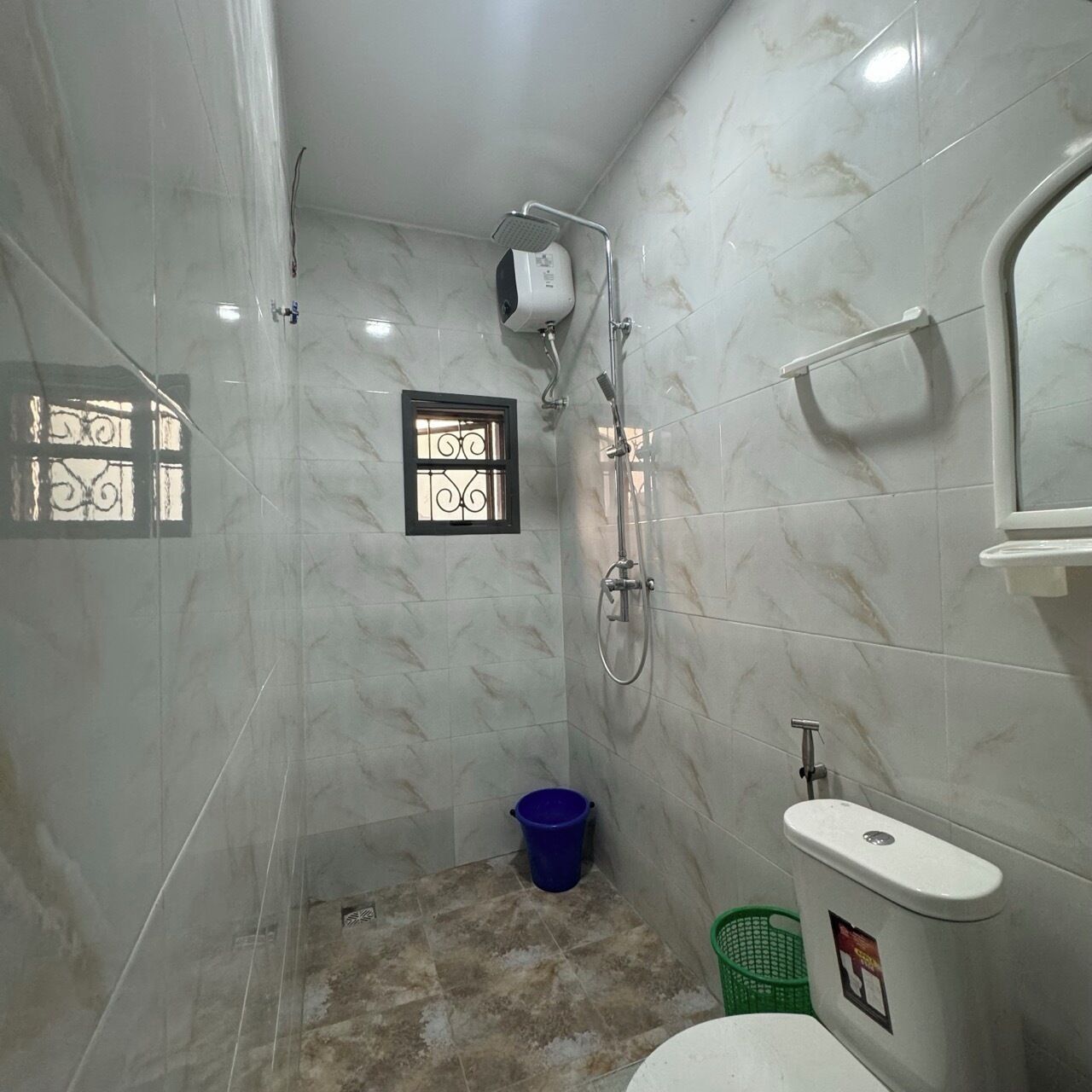 Een kleine badkamer met een douche, toilet en wastafel.