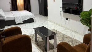 Une chambre d’hôtel moderne équipée d’un lit, d’une télévision, d’un bureau et de deux fauteuils.