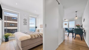 A modern bedroom with a large bed, a view of the sea, and a balcony.