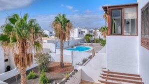 A residential area with a swimming pool, palm trees, and white buildings. - Casa Ondina - Shared pool and Sea view By LVH (Puerto del Carmen)