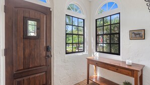 A wooden door with a small window, a wooden bench, and a wall-mounted picture. - Original Davis Islands Spanish Mission Bungalow (Tampa)