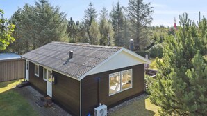 A single-story cabin with a sloped roof, a large window on the front, and a small porch area.