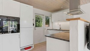 A compact kitchen with white cabinets, a built-in oven, and a window.