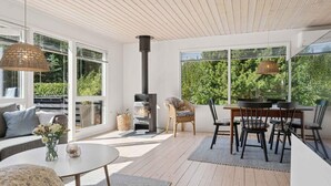 A modern outdoor living space with a built-in wood stove, large windows, and a cozy seating area.