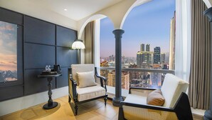 A high-rise room with a city view, a table with a lamp, and a chair with a cushion. - Liberation Monument Riverside HoteL (Chongqing)