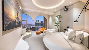 A modern hotel room with a large bed, a seating area with a view of the city, and a flat-screen TV mounted on the wall. - Liberation Monument Riverside HoteL (Chongqing)