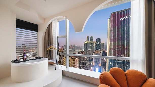 A modern living room with a city view, a white console table, and orange seating. - Liberation Monument Riverside HoteL (Chongqing)